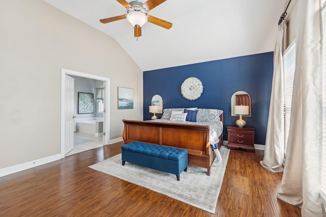 bedroom featuring vaulted ceiling, wood finished floors, baseboards, and connected bathroom