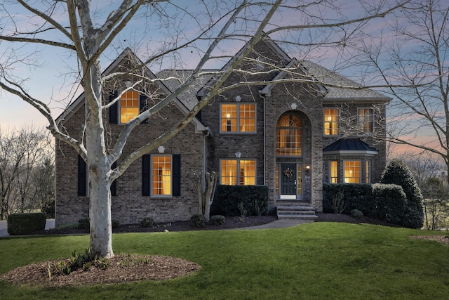 view of front of house featuring a lawn and brick siding