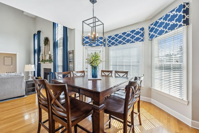 dining room featuring baseboards, an inviting chandelier, and light wood finished floors