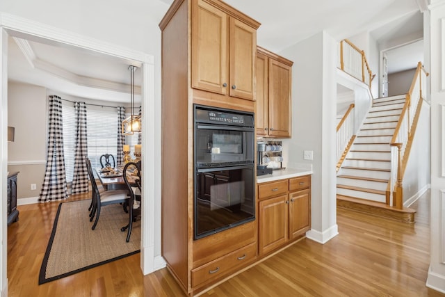 kitchen with baseboards, light countertops, light wood-type flooring, and dobule oven black