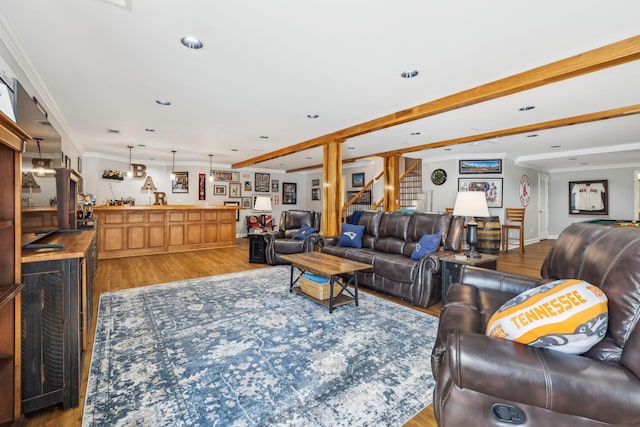 living room with stairway, beamed ceiling, ornamental molding, wet bar, and wood finished floors