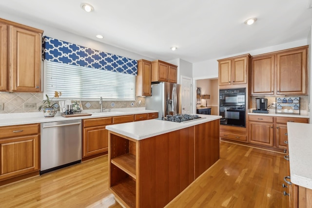 kitchen with a sink, stainless steel appliances, light wood-type flooring, and light countertops