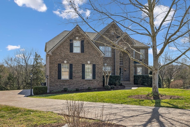 view of front of house featuring brick siding and a front yard