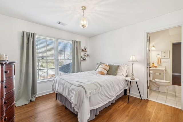 bedroom featuring wood finished floors, visible vents, and baseboards