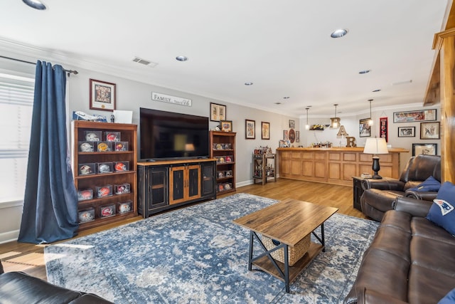 living area with recessed lighting, wood finished floors, visible vents, and ornamental molding