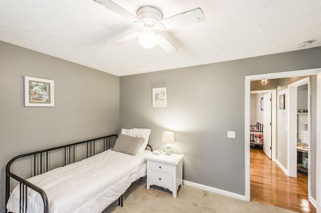 bedroom featuring baseboards, light colored carpet, and a ceiling fan