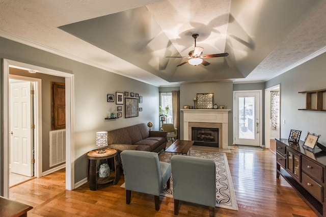 living room with a tray ceiling, plenty of natural light, and wood finished floors