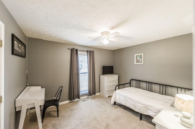 bedroom with visible vents, a ceiling fan, a textured ceiling, baseboards, and light colored carpet