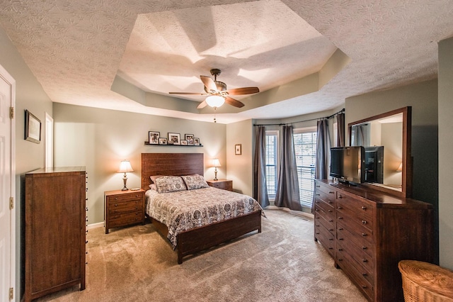 bedroom featuring a textured ceiling, a raised ceiling, baseboards, and light carpet