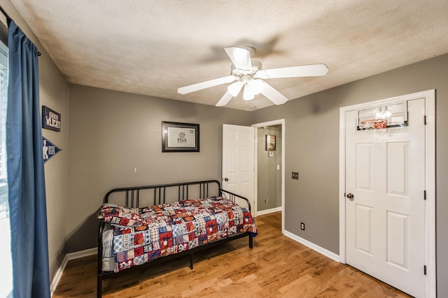 bedroom with baseboards, light wood-style floors, ceiling fan, and a textured ceiling