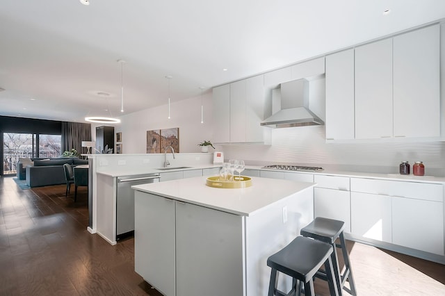 kitchen with a sink, stainless steel dishwasher, a peninsula, wall chimney exhaust hood, and light countertops