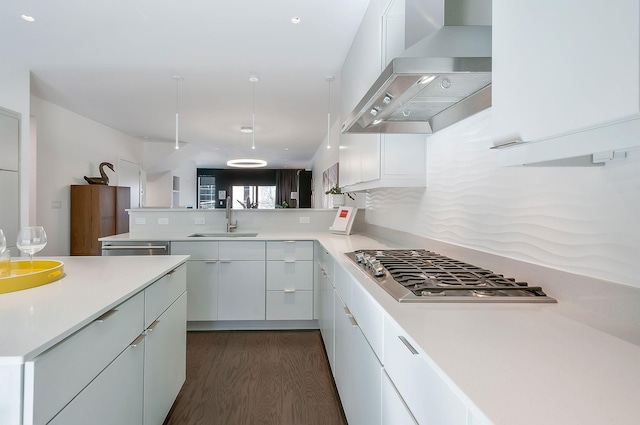 kitchen featuring light countertops, wall chimney range hood, appliances with stainless steel finishes, and a sink