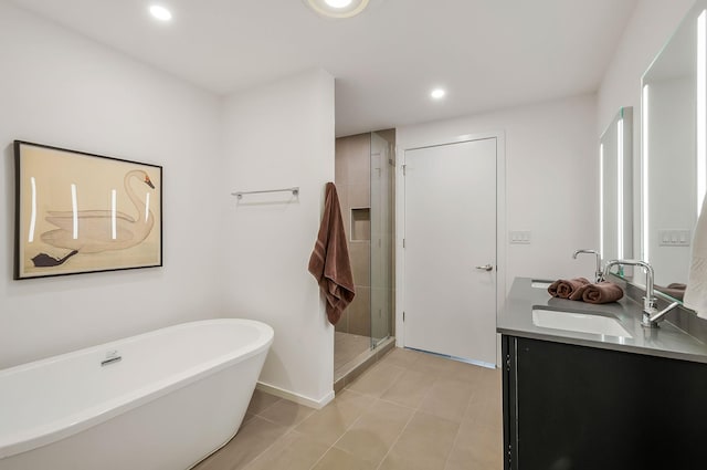 full bathroom featuring a freestanding bath, double vanity, recessed lighting, a stall shower, and a sink