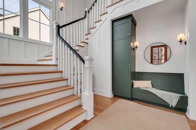 stairs with a decorative wall and wood finished floors