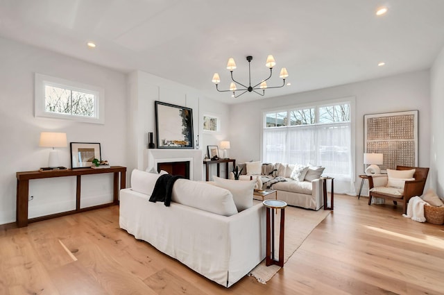 living area with a wealth of natural light, a notable chandelier, light wood-style flooring, and recessed lighting