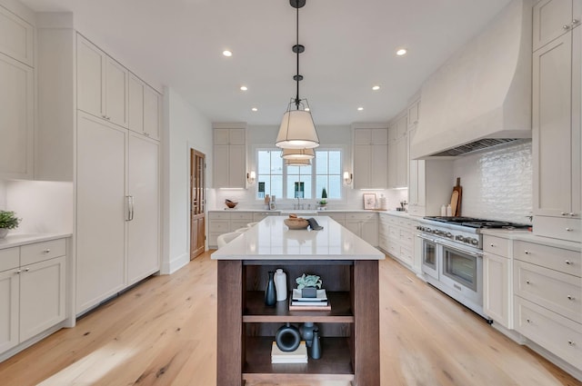 kitchen with double oven range, light countertops, light wood-style floors, custom exhaust hood, and open shelves