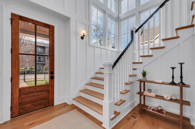 entryway featuring stairs, a decorative wall, and wood finished floors