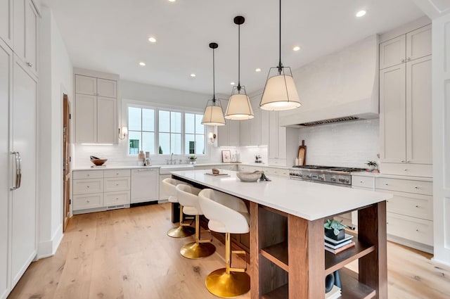 kitchen featuring tasteful backsplash, a kitchen island, white dishwasher, light countertops, and custom exhaust hood