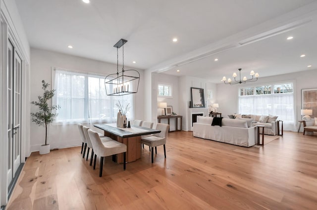 dining space with an inviting chandelier, a wealth of natural light, and light wood finished floors