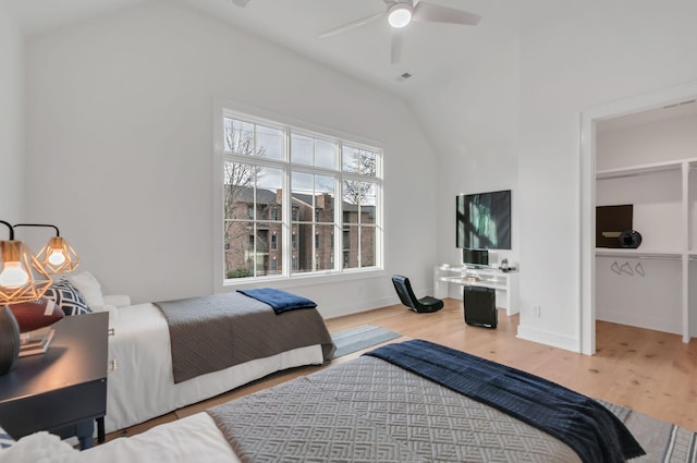 bedroom with a spacious closet, baseboards, lofted ceiling, wood finished floors, and a ceiling fan