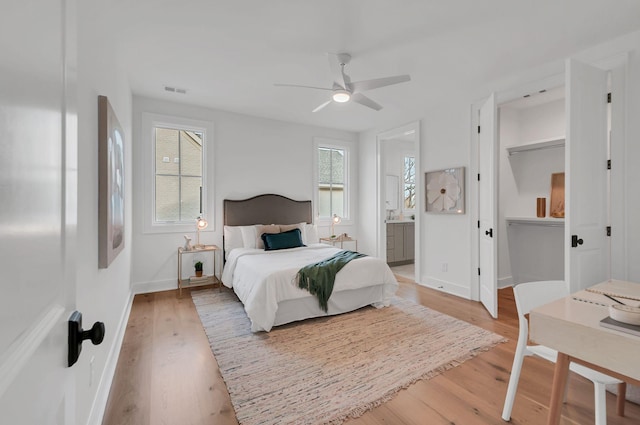 bedroom with visible vents, baseboards, ceiling fan, light wood-style floors, and connected bathroom