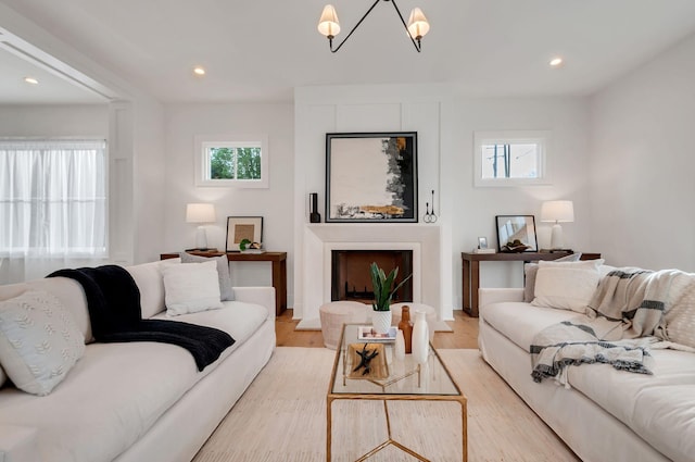 living area with recessed lighting, light wood-style floors, and an inviting chandelier