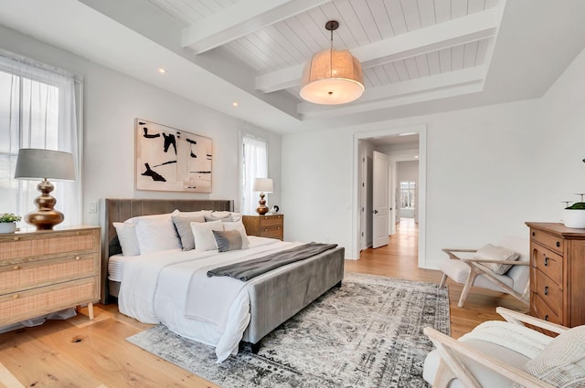 bedroom with beamed ceiling, multiple windows, baseboards, and light wood-style flooring