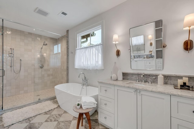 full bathroom with vanity, a shower stall, a freestanding tub, and visible vents