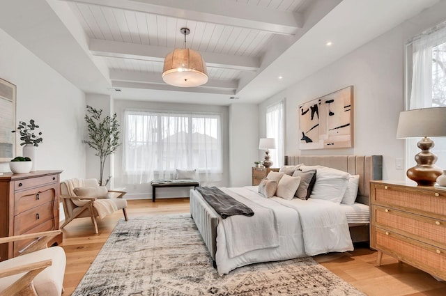 bedroom with beamed ceiling, light wood-style floors, and baseboards