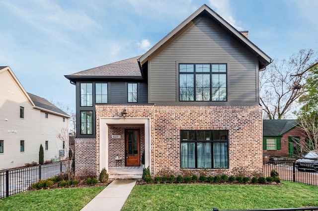 view of front of house featuring brick siding, a front lawn, and fence