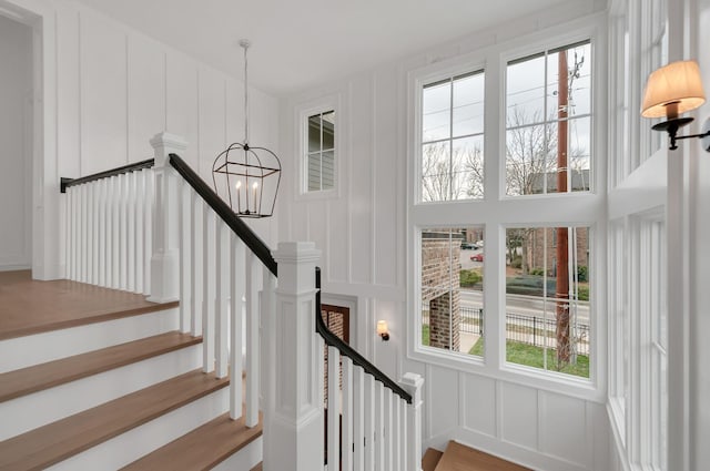 stairway with a notable chandelier and a decorative wall