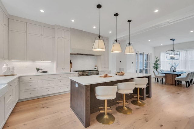 kitchen featuring decorative backsplash, extractor fan, light wood-style flooring, and a center island