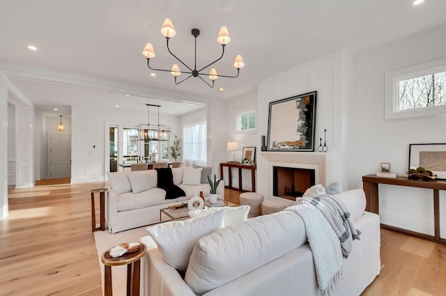 living room featuring recessed lighting, light wood-type flooring, baseboards, and a chandelier