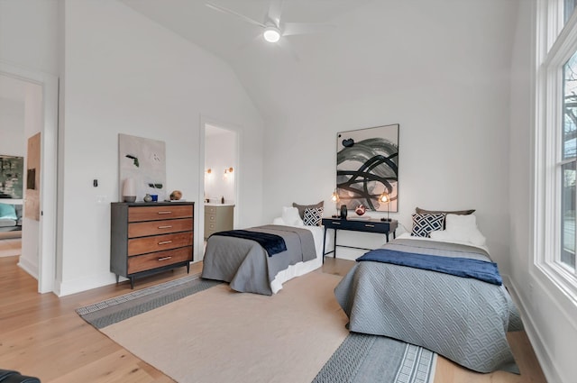 bedroom with wood finished floors, baseboards, ensuite bathroom, and high vaulted ceiling