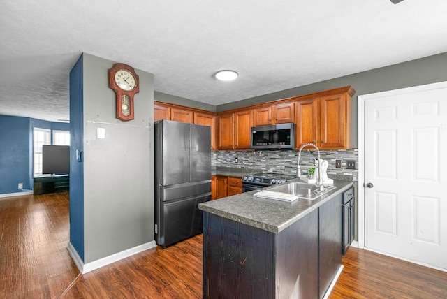 kitchen featuring dark wood finished floors, brown cabinetry, appliances with stainless steel finishes, and a sink