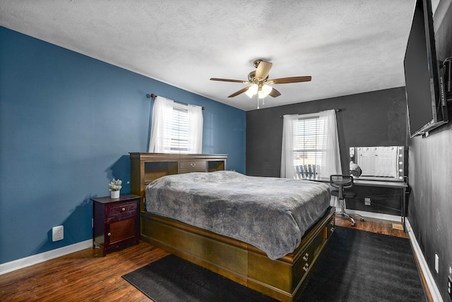 bedroom with baseboards, multiple windows, a textured ceiling, and dark wood finished floors