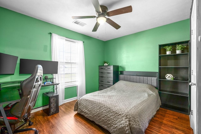 bedroom featuring visible vents, a ceiling fan, baseboards, and wood finished floors