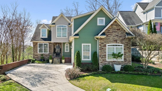 craftsman house featuring a front yard, fence, and stone siding