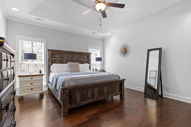 bedroom with dark wood finished floors, multiple windows, and a raised ceiling