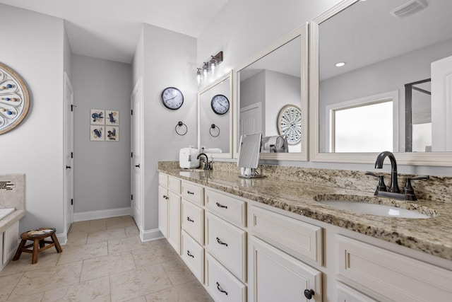 bathroom with double vanity, visible vents, baseboards, and a sink