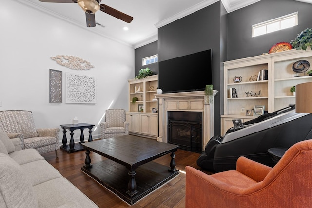 living area with dark wood finished floors, a fireplace with flush hearth, ceiling fan, and ornamental molding