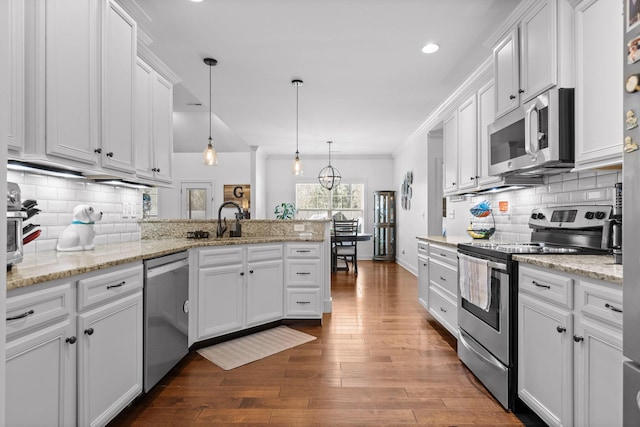 kitchen with white cabinetry, a peninsula, stainless steel appliances, and dark wood-type flooring