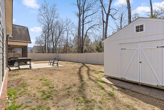 view of yard featuring an outbuilding, a fenced backyard, a shed, and a patio area