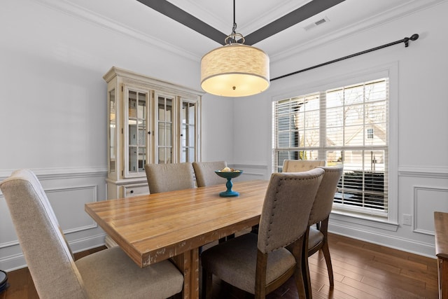 dining area featuring a wainscoted wall, dark wood-style floors, crown molding, and a decorative wall