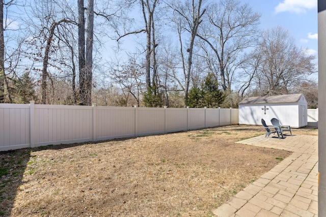 view of yard featuring an outdoor structure, a fenced backyard, a shed, and a patio