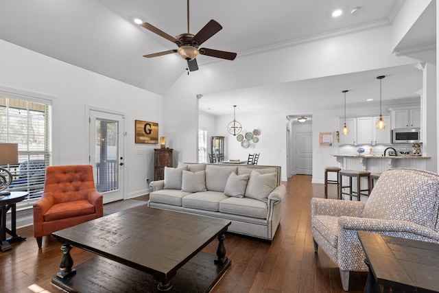 living room featuring dark wood finished floors, high vaulted ceiling, crown molding, and a ceiling fan