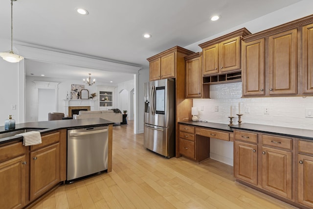 kitchen with dark countertops, brown cabinets, appliances with stainless steel finishes, and light wood-style floors