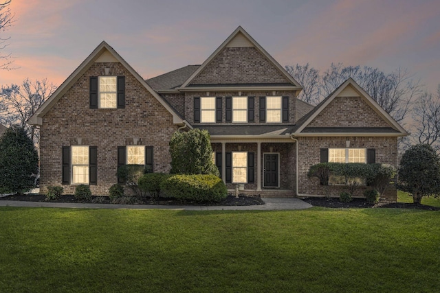 view of front of house with brick siding, roof with shingles, and a front yard