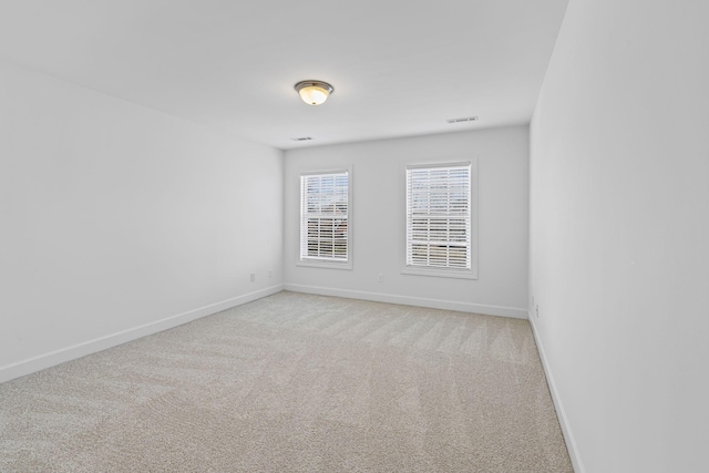 spare room featuring baseboards, light carpet, and visible vents