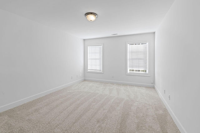 spare room with visible vents, light colored carpet, and baseboards